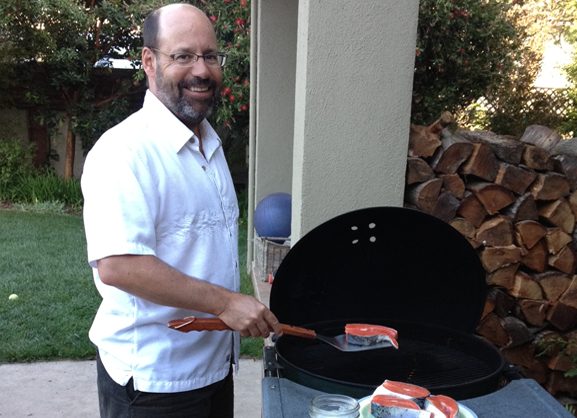 Man grilling fish outside on a grill
