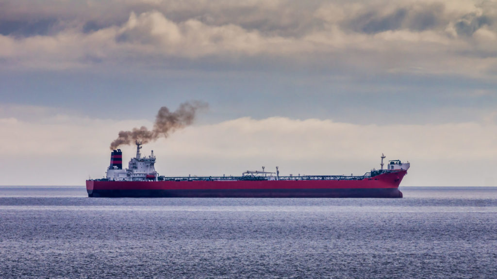 Red oil tanker anchored offshore and running its engines