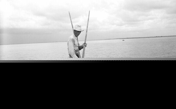 Man "tonging" for oysters from barge.