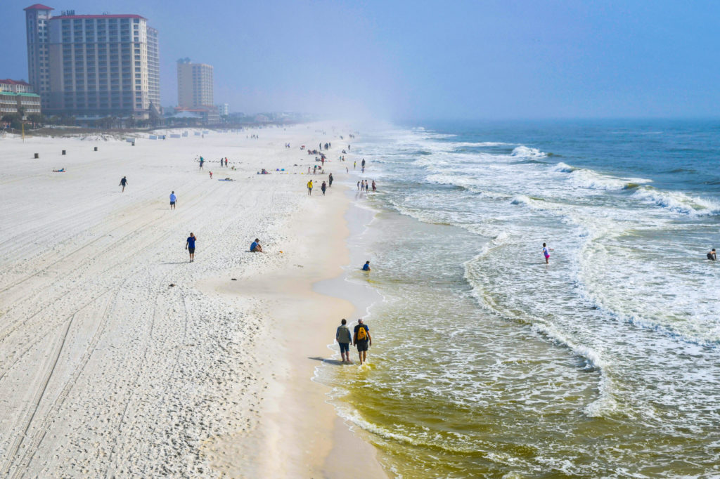 Beachgoers walking along the shoreline at Pensacola Beach.