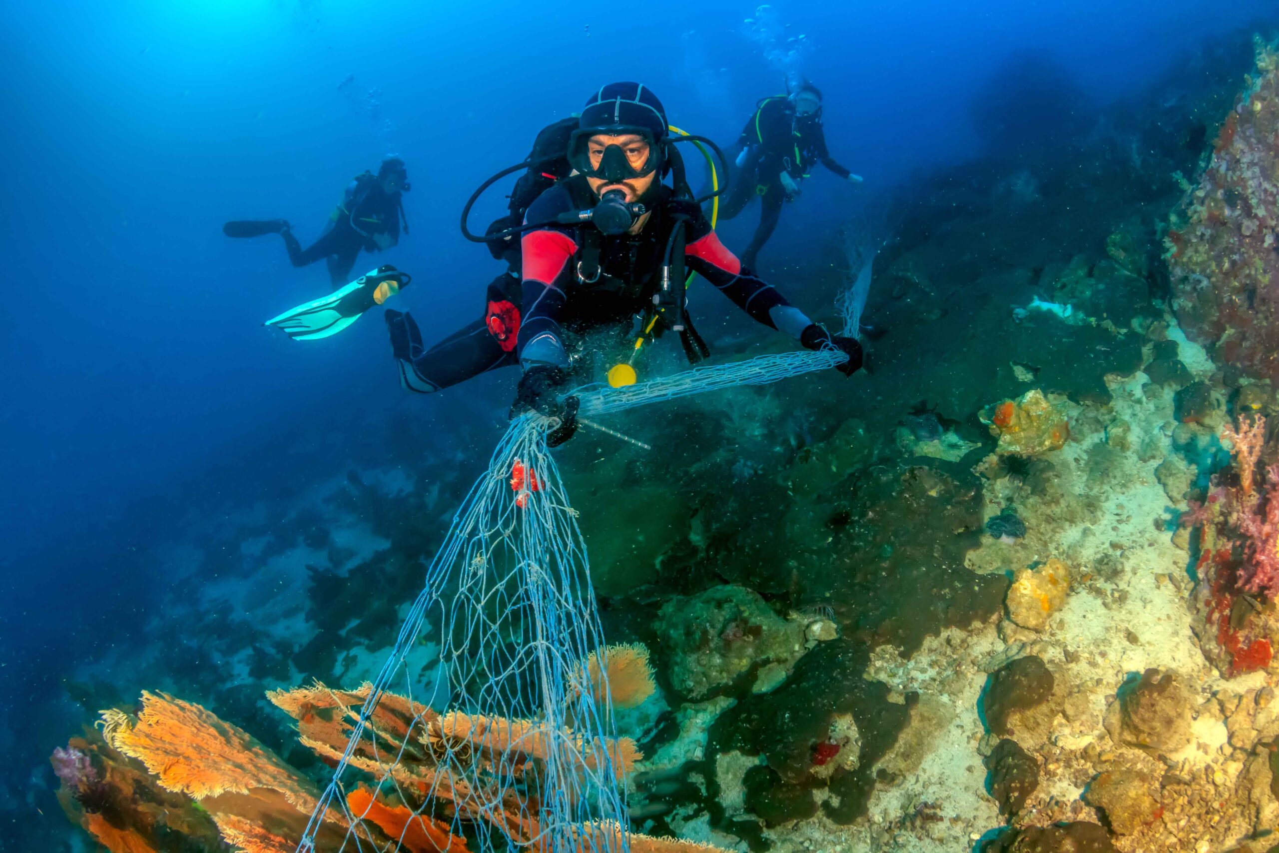 SCUBA divers attempting to remove a huge ghost fishing net tangl