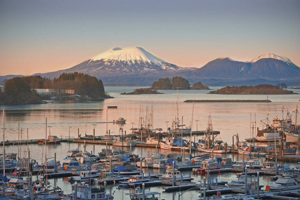 Fishing boats sit in the water with beautiful mountains behind them
