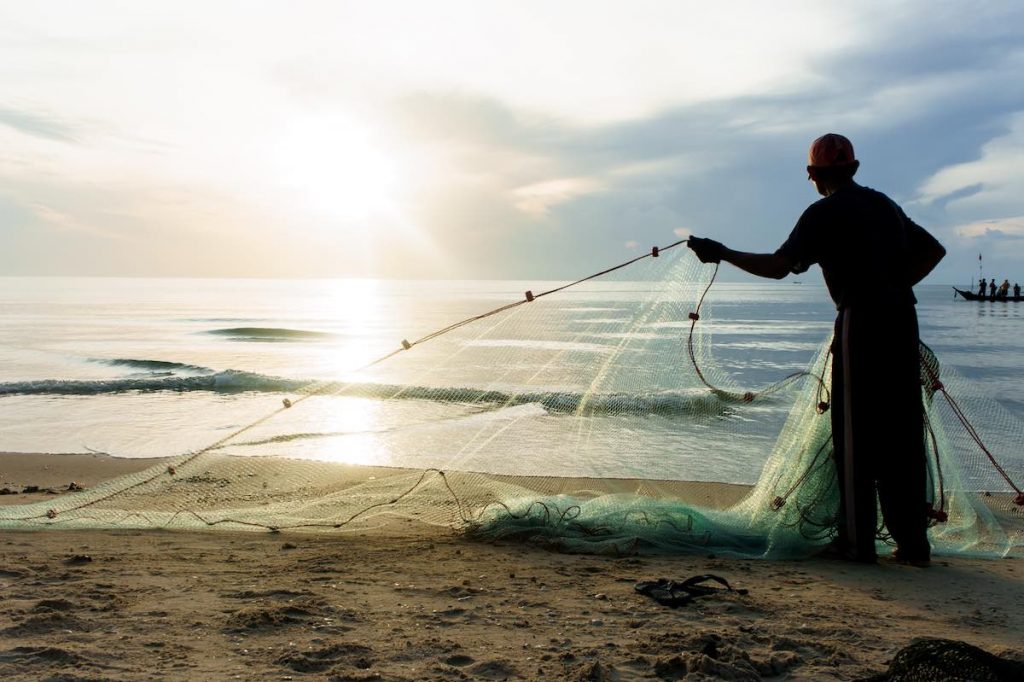 Silhouette fisherman working on beach in morning