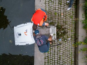 Aerial perspective of two people working on a trash trap device.